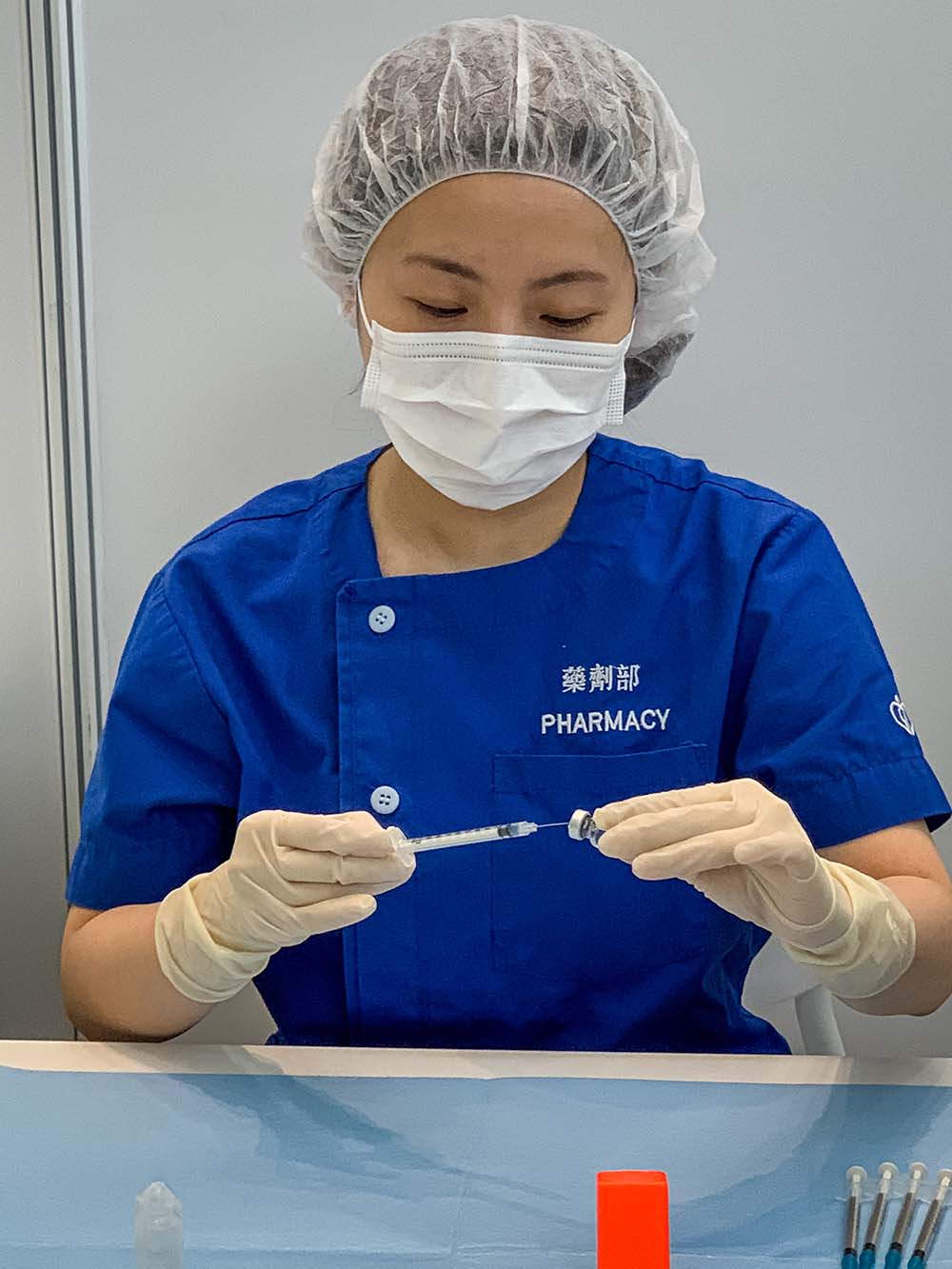 藥劑部人員用針筒抽取已稀釋的疫苗，並貼上標籤